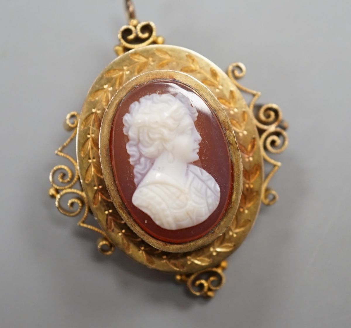 A Victorian style yellow metal and hardstone cameo set oval hardstone pendant brooch, 37mm, gross 6.9 grams.